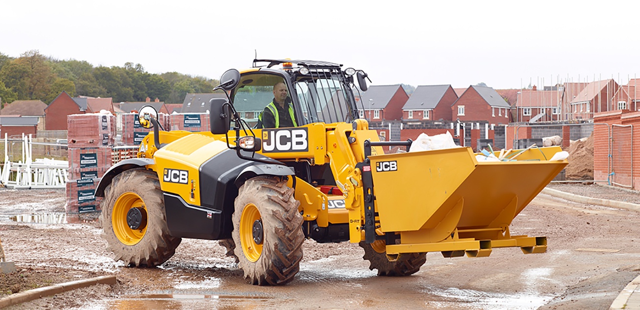 JCB telehandler carrying a skip on its forks