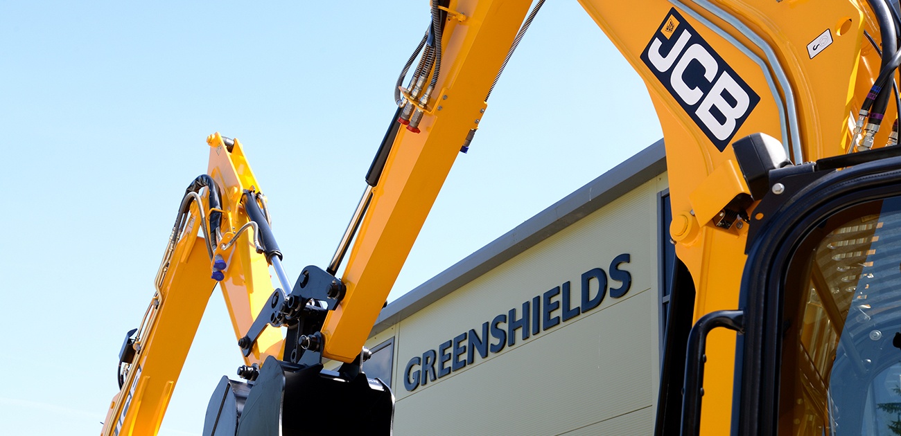 JCB excavator booms in an arch over the Greenshields logo