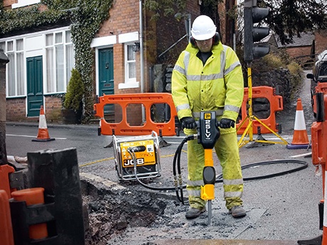 a worker hammering the road with a HM25LV breaker