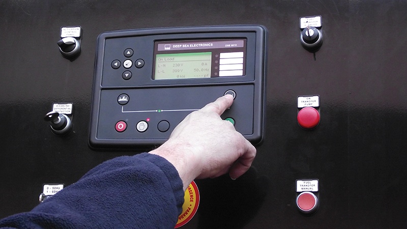 Generator control panel with hand pressing a button