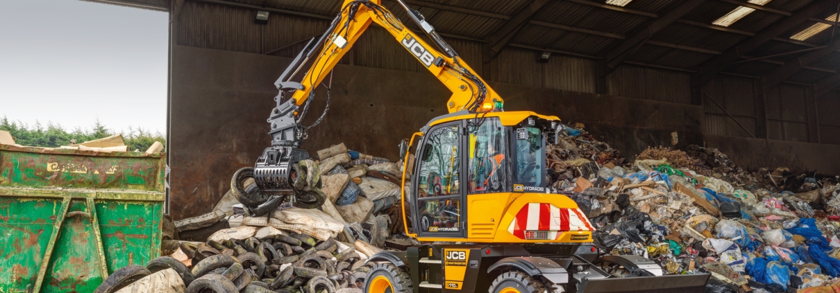 A JCB Hydradig 110W Wheeled Excavator lifting tyres with a grab