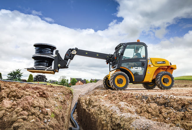 JCB 520-40 Telehandler extending its boom across a trench with some piping on its forks 
