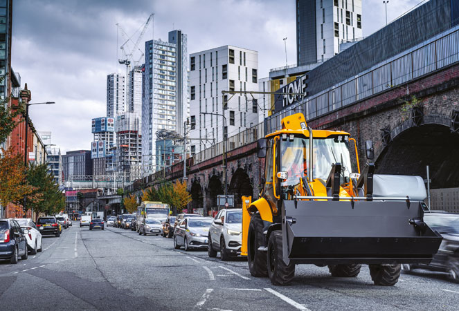 JCB 3CX Pro Backhoe Loader driving through a city
